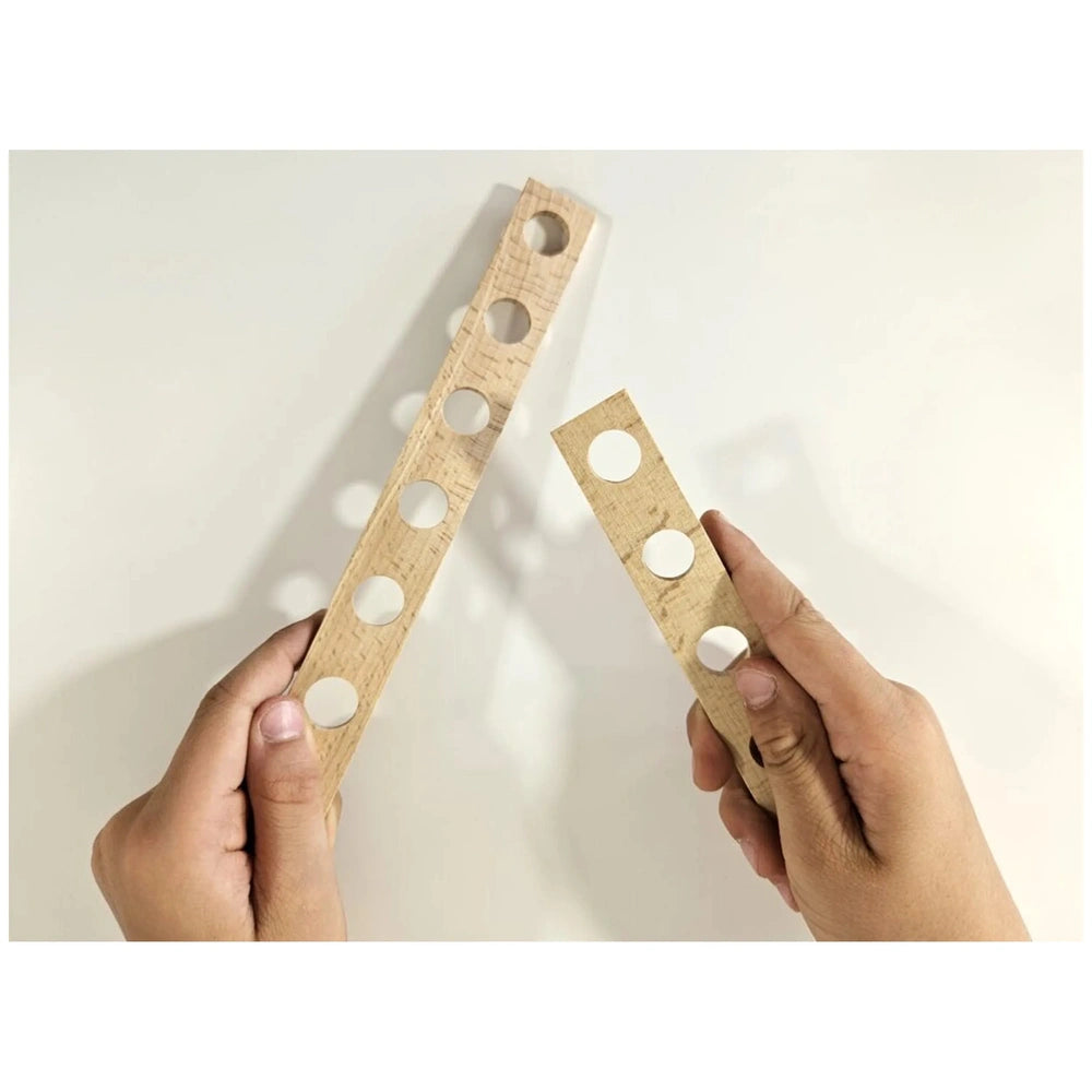 Hands holding two wooden boards with pre-drilled holes from the Alexander Maly Constructor Junior Race Car set.