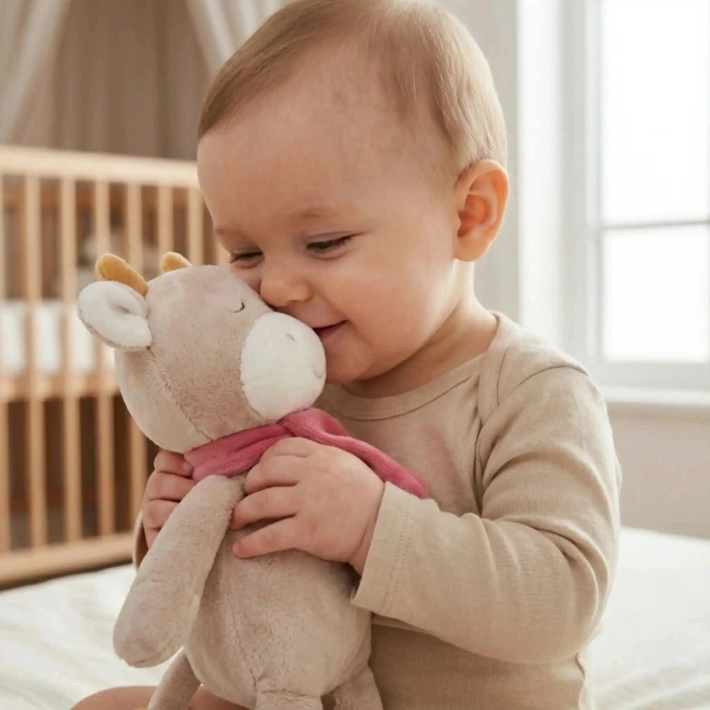 Artesavi Cow Plush Rattle held by a smiling child in a softly blurred indoor setting, exuding warmth and affection.