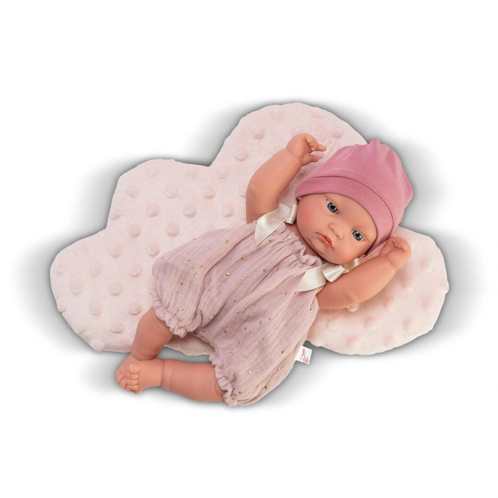 Gordi doll in a pink romper and hat, resting on a plush pink cloud cushion.