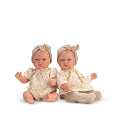 Two 30 cm ASI Dolls wearing floral outfits and matching headbands, sitting side by side with articulated limbs.