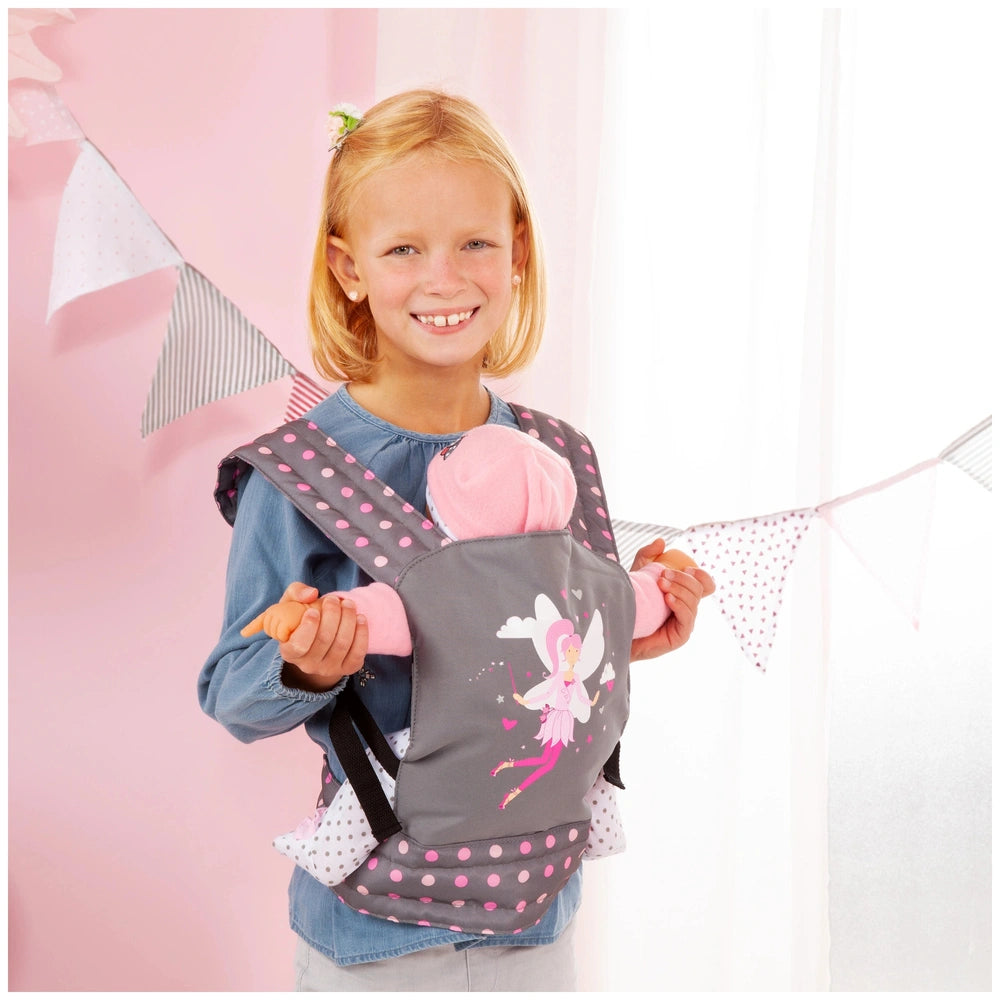 BAYER DESIGN doll carrier in gray and pink, held by a blonde girl in a blue top, with a baby in a pink outfit.