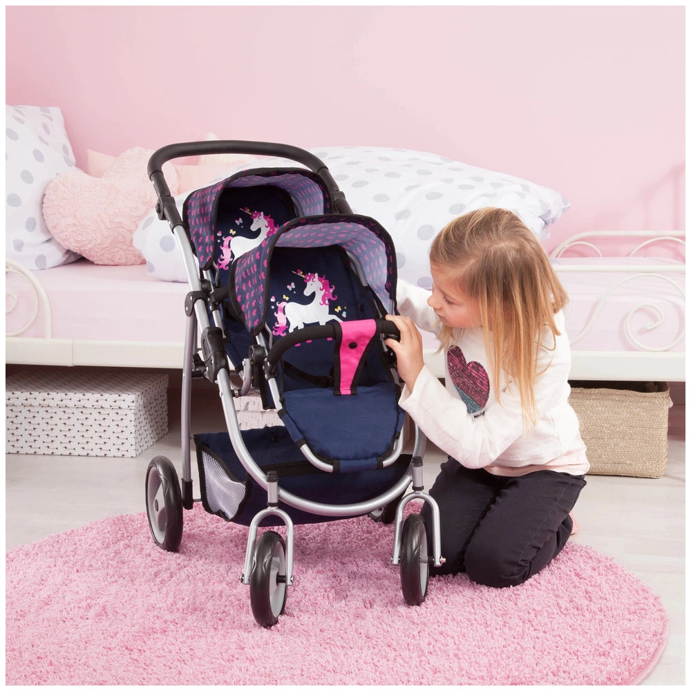 BAYER DESIGN Twin Pram in unicorn print with pink base, shiny frame, and young girl playing on soft pink carpet.