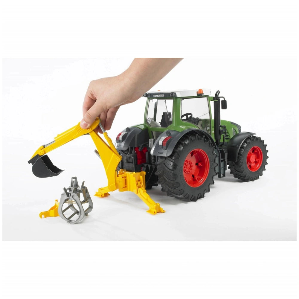 Hand attaching yellow hydraulic arm to green toy tractor with red wheels, showing accessory versatility.