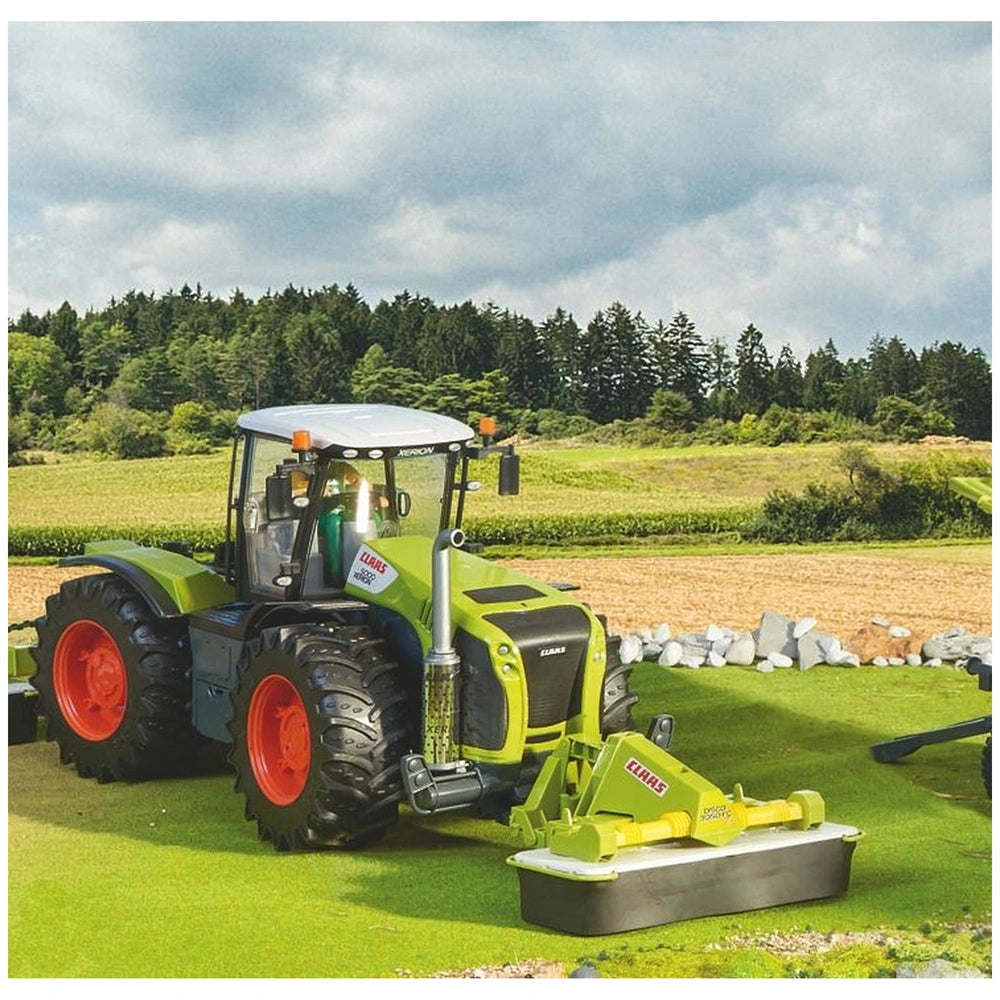 Claas toy tractor with front disc mower on green field, featuring realistic details and vibrant colors, against a forest backdrop.