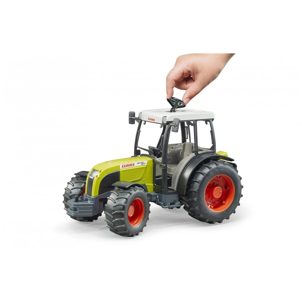 Hand adjusting the roof of a green and white Bruder Claas Nectis 267 F toy tractor with red wheels.