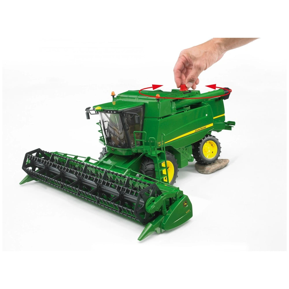 Green Bruder John Deere T670i combine harvester toy with a hand rotating the red knob on top.