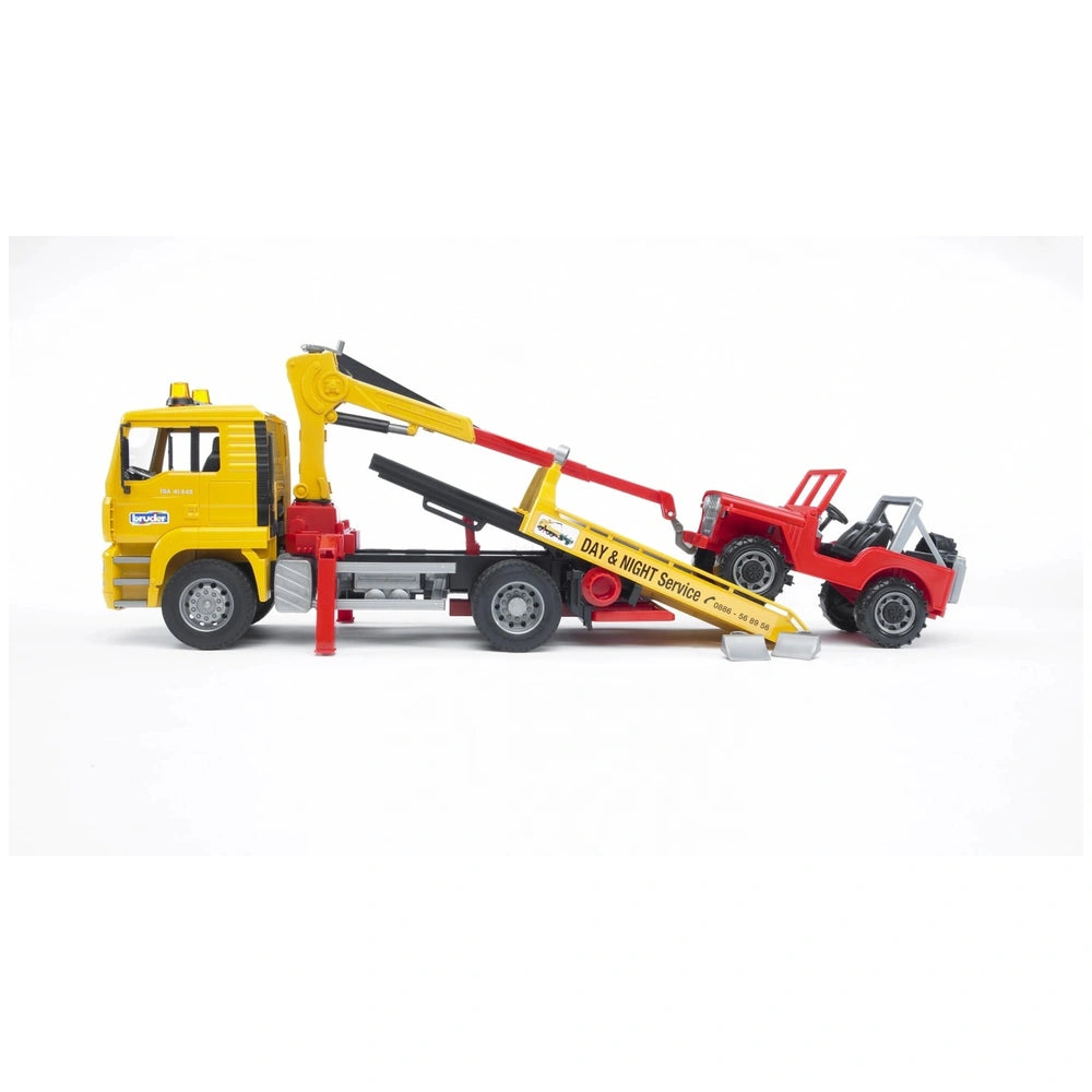 Yellow Bruder MAN TGA breakdown truck with extendable crane towing a red cross-country vehicle, side view.