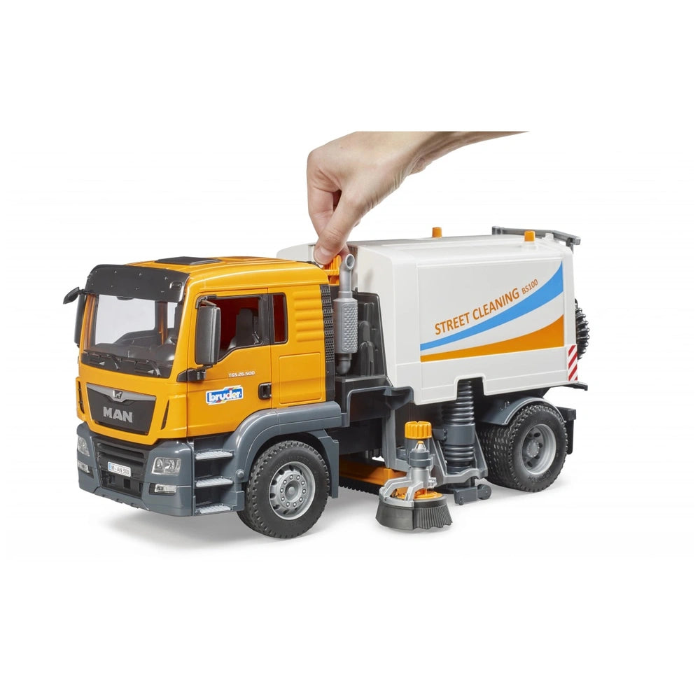 Hand interacting with Bruder MAN TGS Street Sweeper toy, showcasing detailed orange and white design with movable parts.