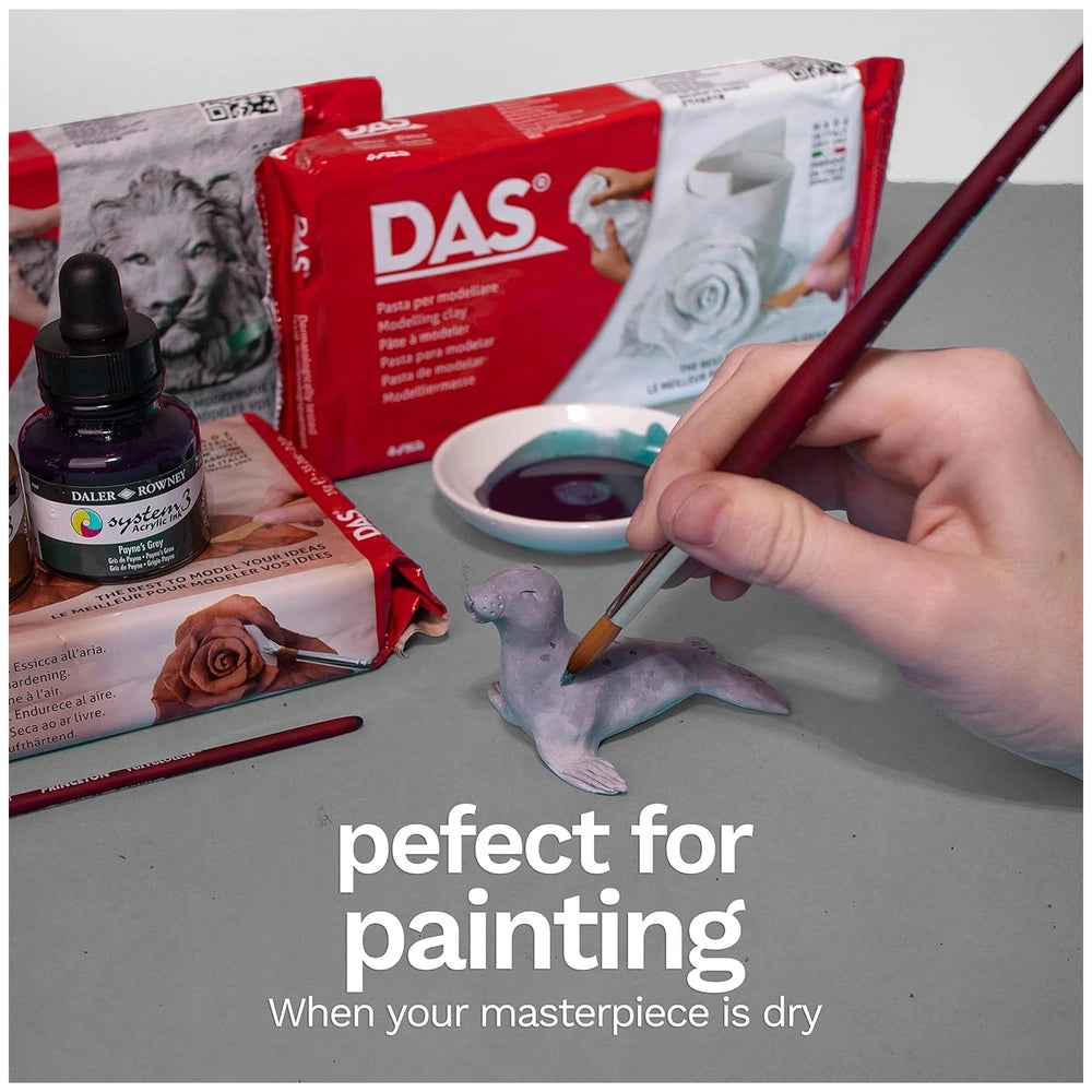 Das Modeling Clay - Terra-Cotta 500 Gr. displayed alongside a paintbrush dipped in dark paint, painting a gray seal figurine.