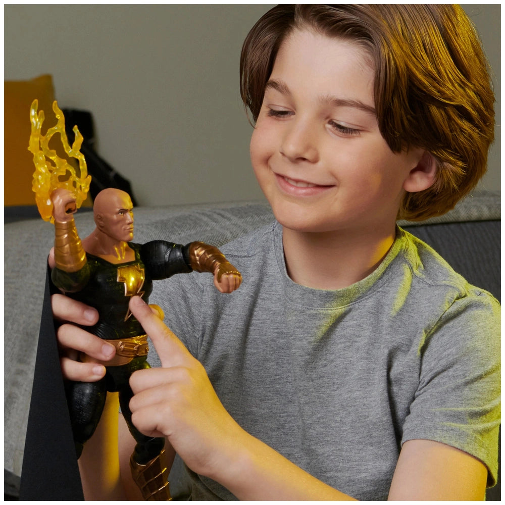 DC Comics Black Adam action figure with metallic sheen held by a smiling boy indoors, showcasing its black and gold details.