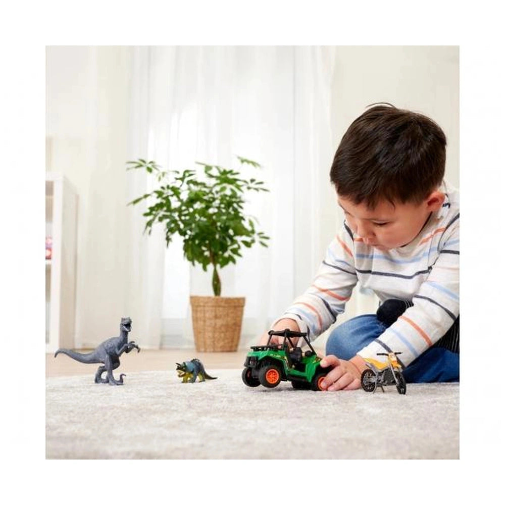 Boy playing with Dickie Dino Tracker Explorer Toy Playsets, featuring a green car, gray dinosaur, and yellow motorcycle.