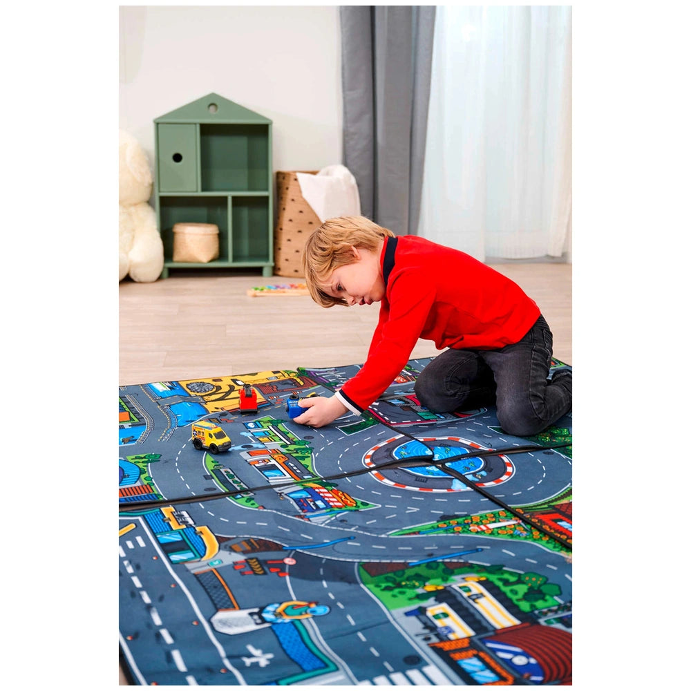 Dickie playmat featuring colorful vehicles, with a child in a red shirt sitting on a gray carpet beside a green toy box.