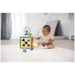 Eichhorn Color Little Play Center features a colorful toy box beside a baby sitting on a fluffy white rug indoors.