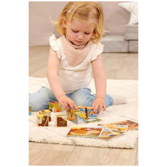 Eichhorn cubes and puzzles are scattered around a young girl with blonde hair, engaging playfully on a soft white rug.