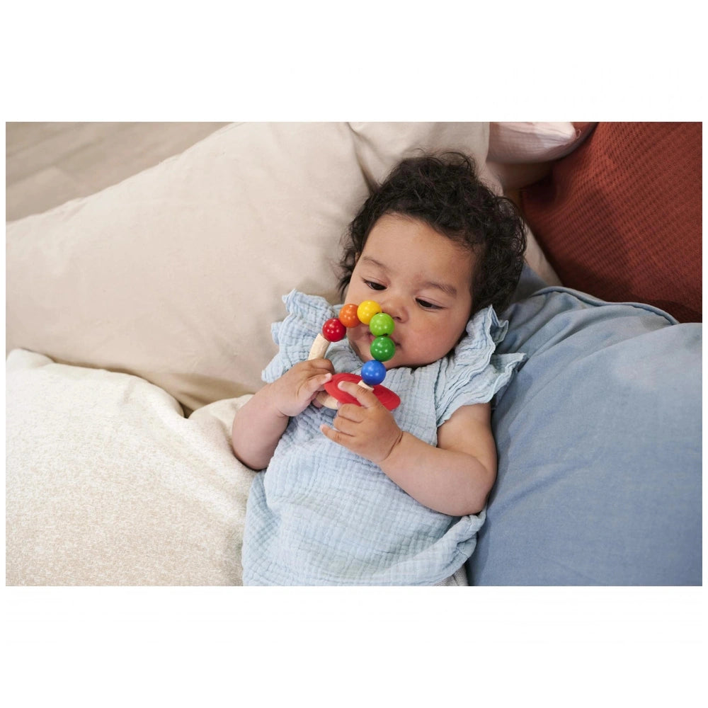 Eichhorn Eh Baby Wooden Teething Ring in a cozy setting with a young child gently sleeping, pacifier included.