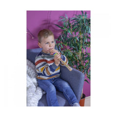 Eichhorn Music Wooden Flute with a child in a colorful sweater playing it on a blue couch in a cozy, decorated room.