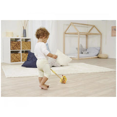 Eichhorn Push Bee toy in a bright room with a child, wooden playhouse, and minimalistic decor featuring natural materials.