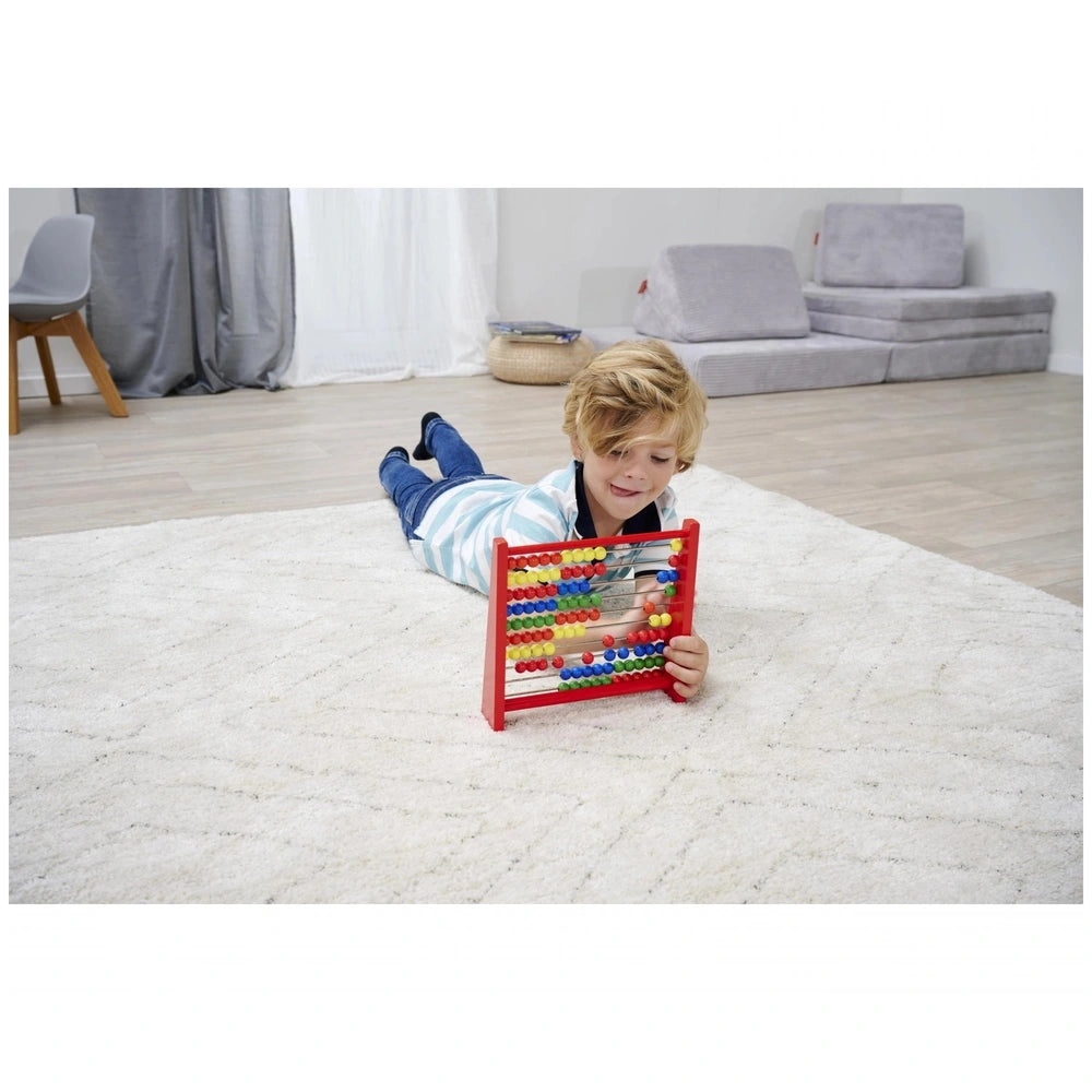 Eichhorn Wooden Slide Rule educational toy being used by a young boy on a light carpeted floor in a modern room.