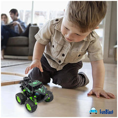 Dinosaur-themed Ginmar monster truck in green and black, played with by a light-skinned child on light hardwood flooring.