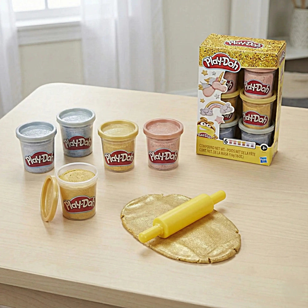 Play-Doh Metallics Compound Collection displayed on a gold foil, featuring colorful plastic containers and a light wood table
