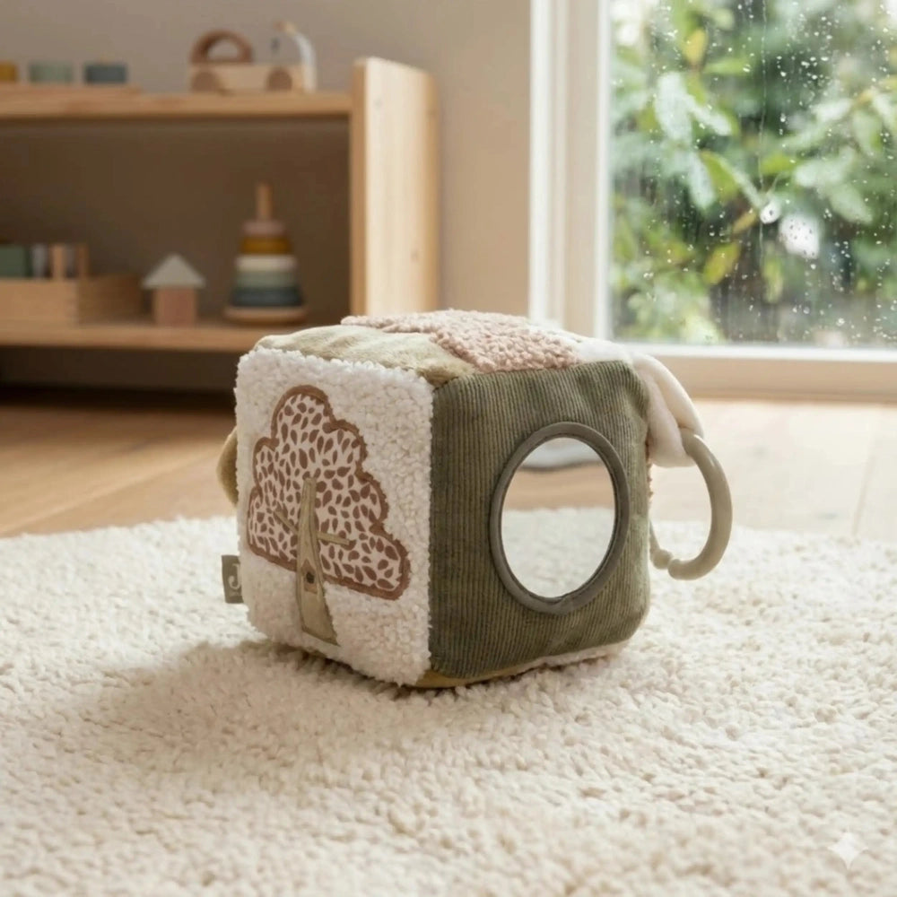 Jollein Activity Cube Tiny Park features a round window and gray handle, set on a white rug with wooden flooring.