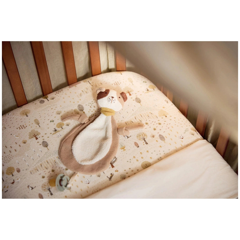 Jollein Pacifier Cloth Mick on light beige patterned bedding with a stuffed animal featuring a light brown head and white bod