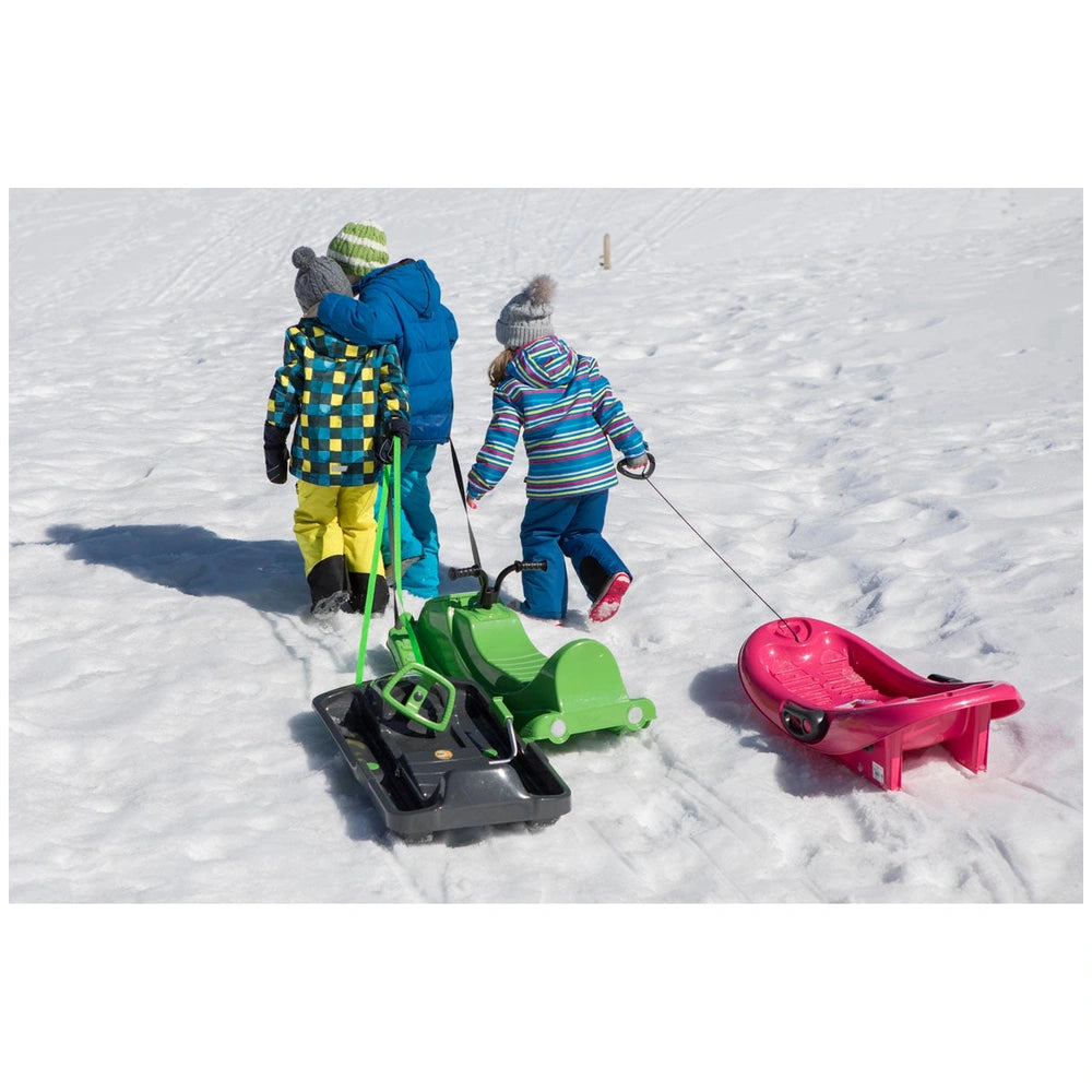 KHW Snow Fox sleds in green and pink are held by two children in winter clothing on fresh white snow.