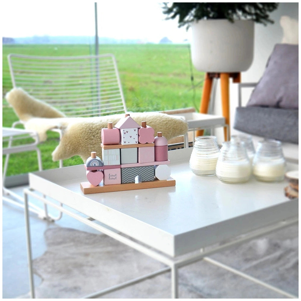 Label-Label Stacking Blocks House on a white coffee table in an outdoor setting with various colorful toys and glass jars.