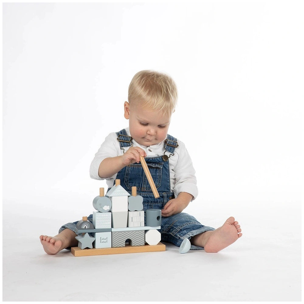 Label-Label stacking blocks house with gray and white wooden blocks, child in blue overalls, and wooden hammer in lifestyle s
