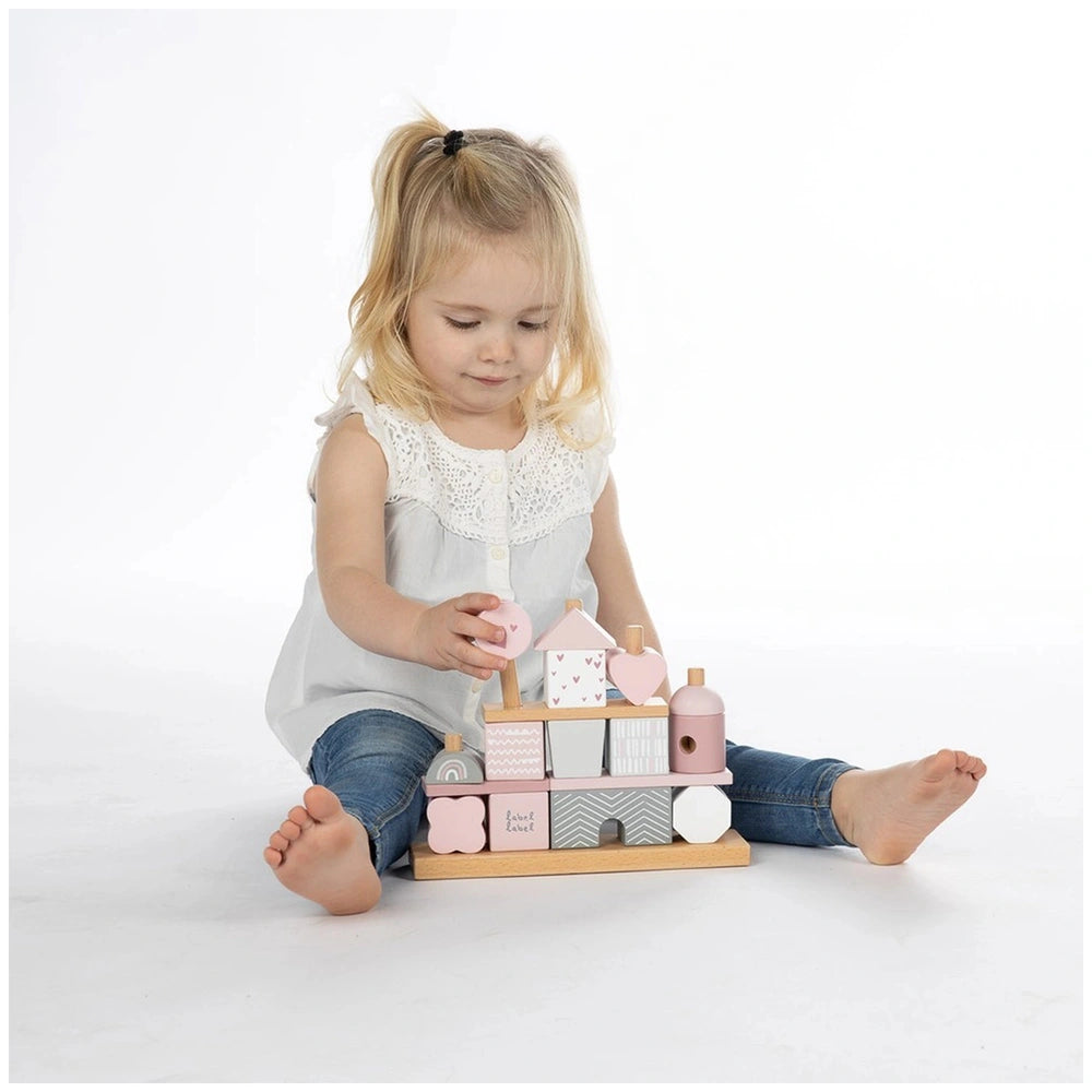 Child playing with Label-Label stacking blocks house on a wooden surface, showcasing vibrant toy components in a lifestyle se