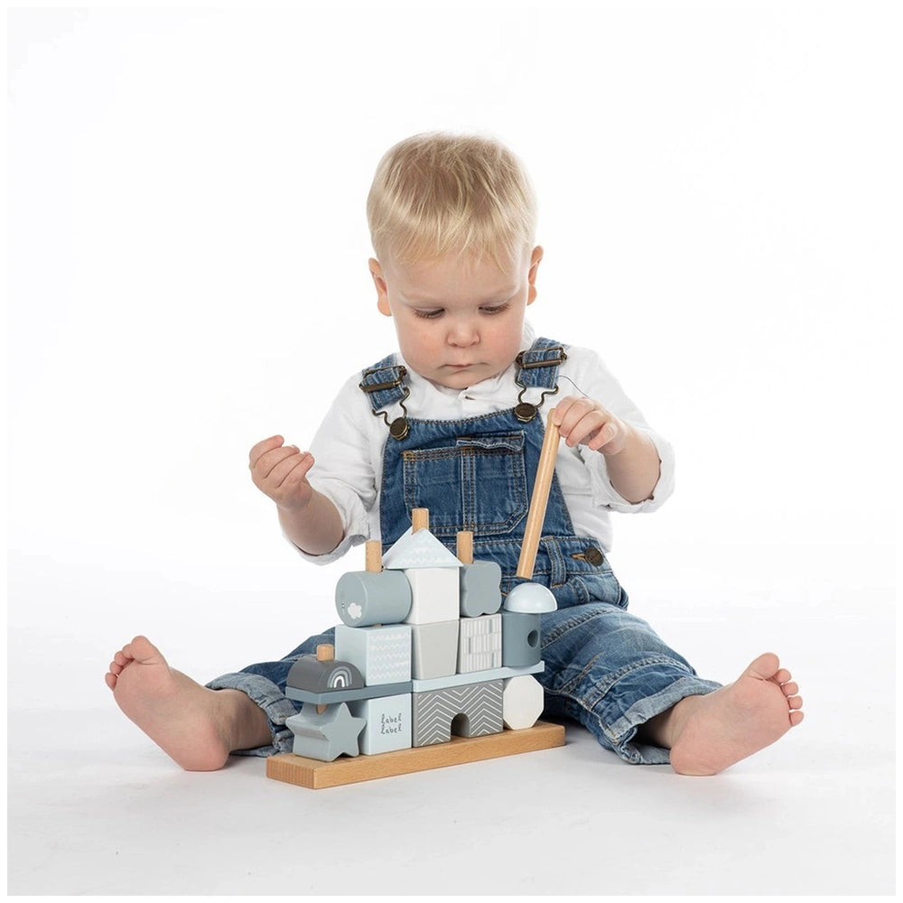Label-Label stacking blocks house with gray roof and door, held by a child in blue overalls and white shirt on a white surfac