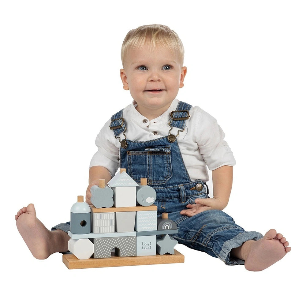 Label-Label stacking blocks house with a child in denim overalls, holding a colorful wooden block featuring shapes and the na