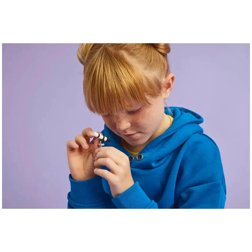 Lego Animal Crossing construction set features a girl in a blue hoodie examining a small toy against a light purple backgroun