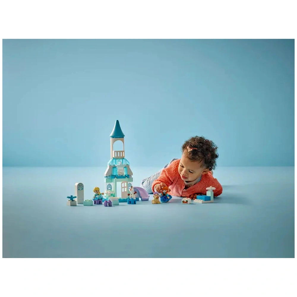 LEGO Anna and Elsa's Frozen Castle Party set displayed as a child plays on a light blue surface, fully engaged with the toys.