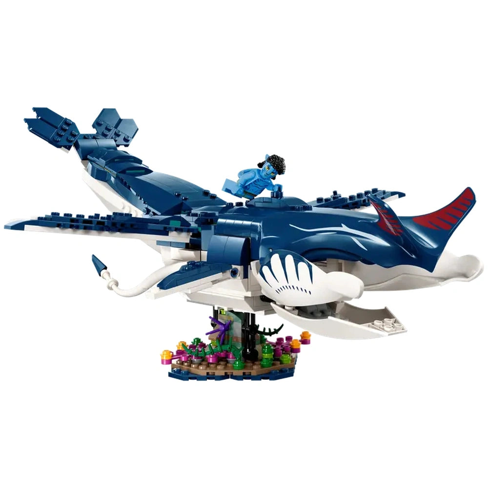 A blue LEGO® tulkun figure with a red tail and white markings, carrying a minifigure, hovers over a colorful seabed scene.
