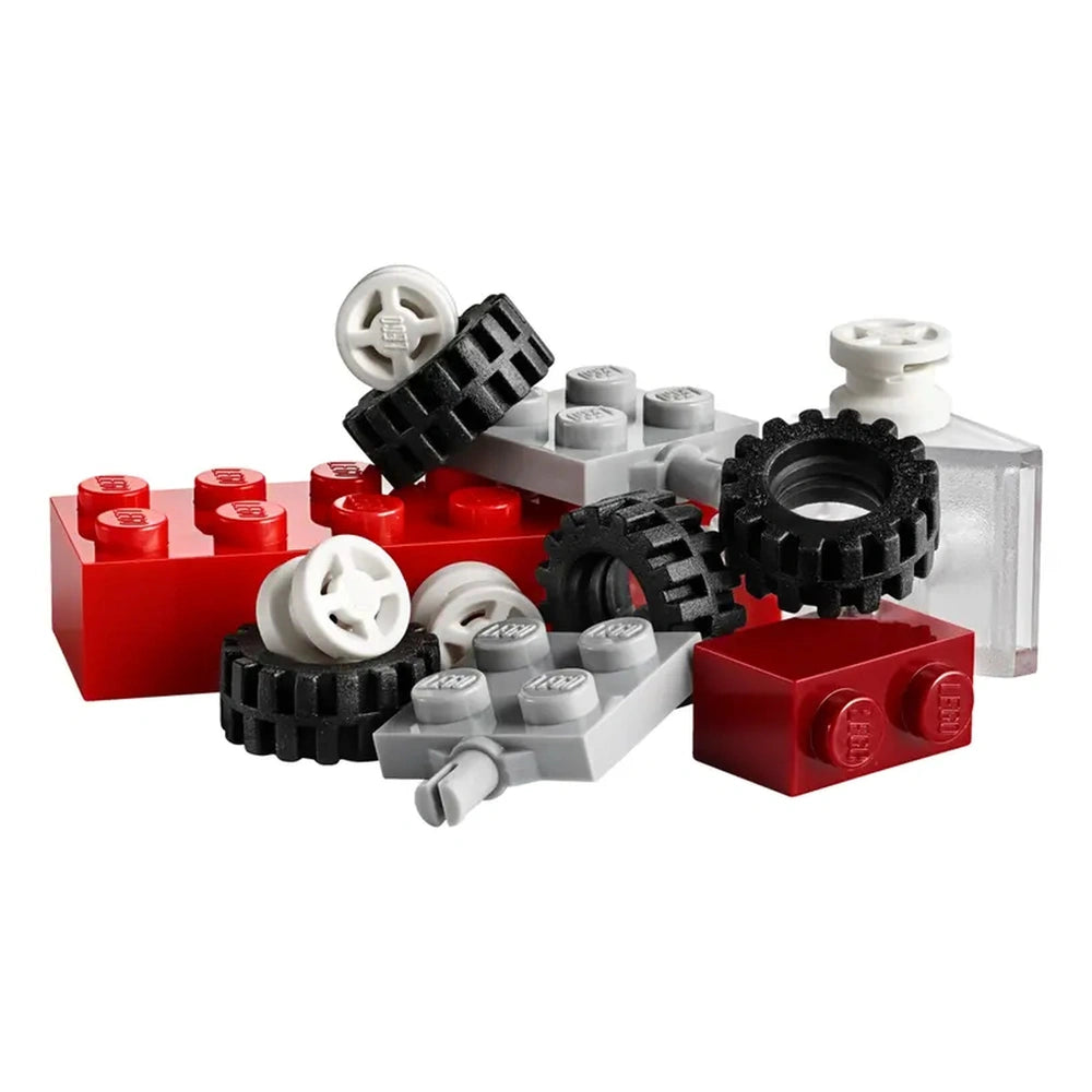 Colorful LEGO bricks in various shapes, including black tires, red and gray blocks, arranged in a playful pile.