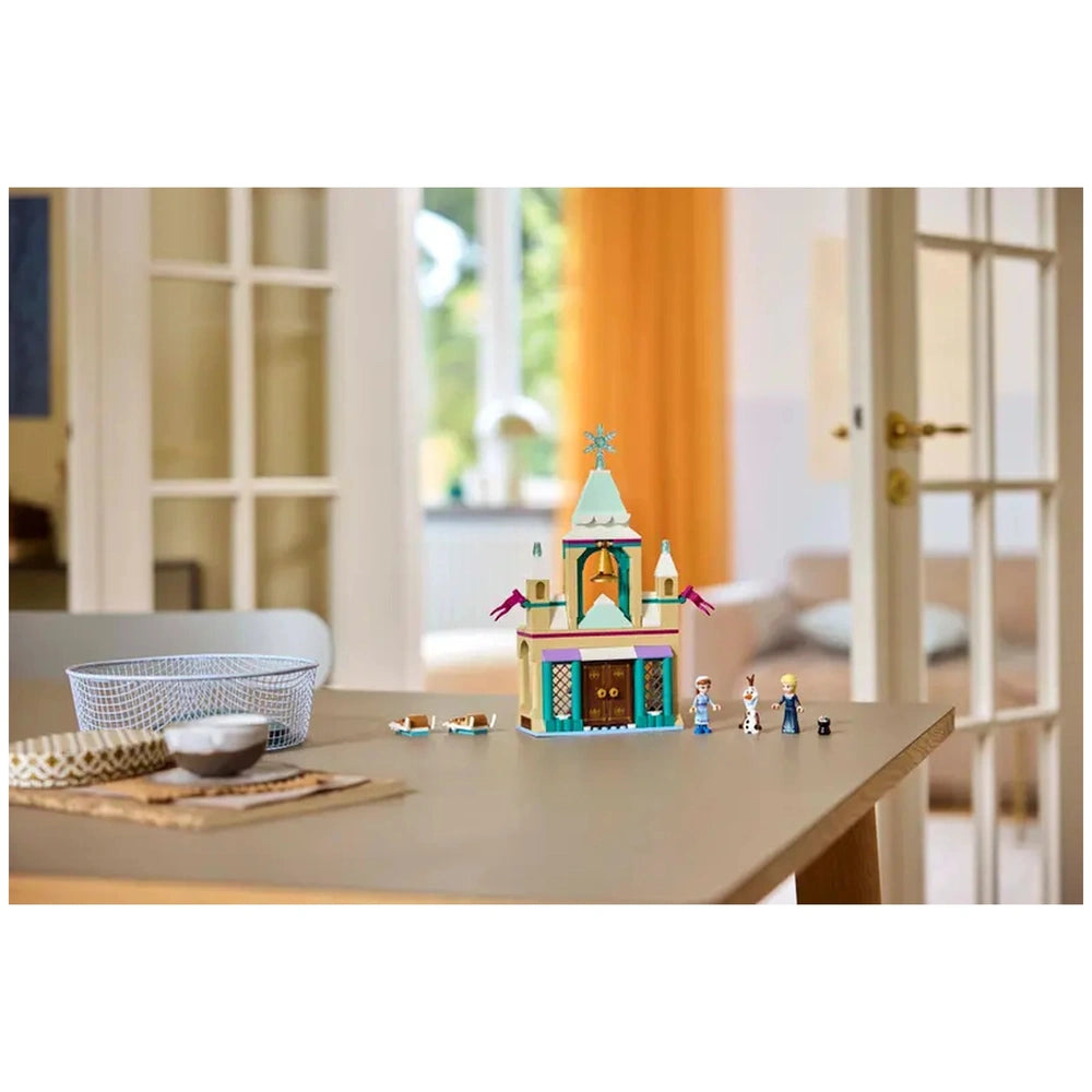 Colorful LEGO Disney Frozen Arendelle Castle set on a wooden table, featuring Elsa, Anna, and Olaf figures, with a cozy room backdrop.
