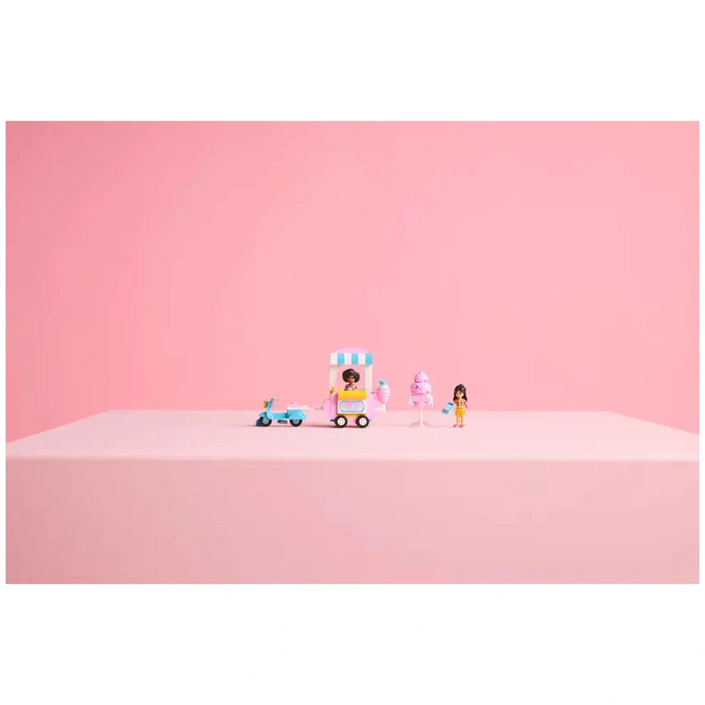 LEGO Friends cotton candy stand set featuring two minifigures, a pink food cart, a scooter, and cotton candy accessories on a pink background.