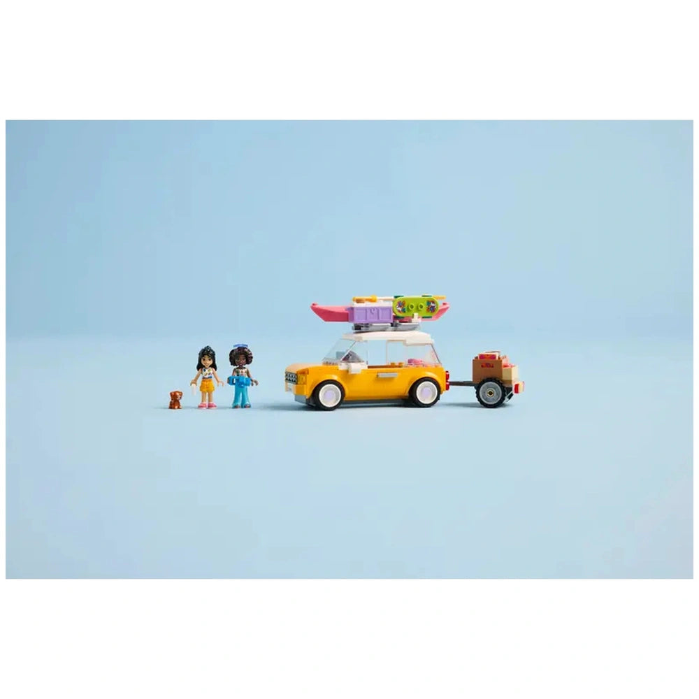 LEGO Friends travel car in vibrant yellow, with a pink kayak on top, beside two mini-doll figures and a small brown puppy.