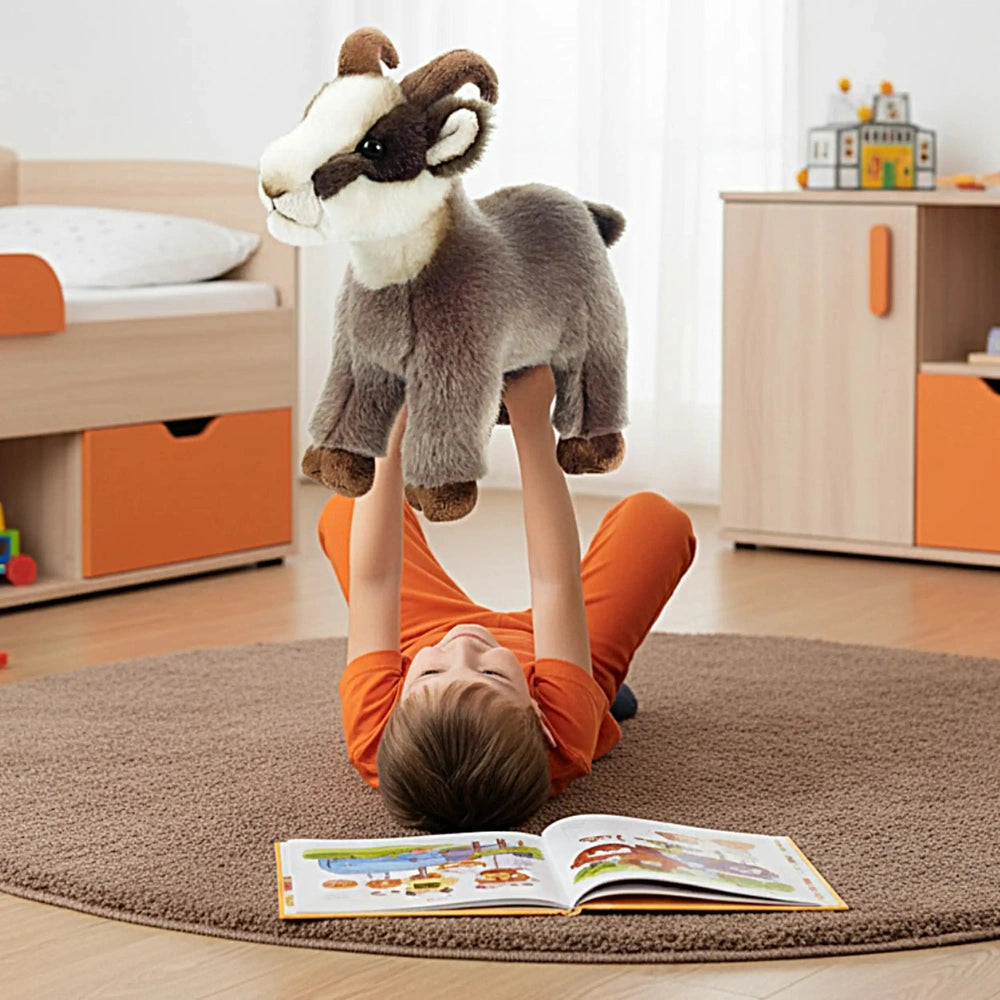 Rudy Little Mountain Chamois plush toy on a wooden bed frame with a young boy playing on a carpeted floor.