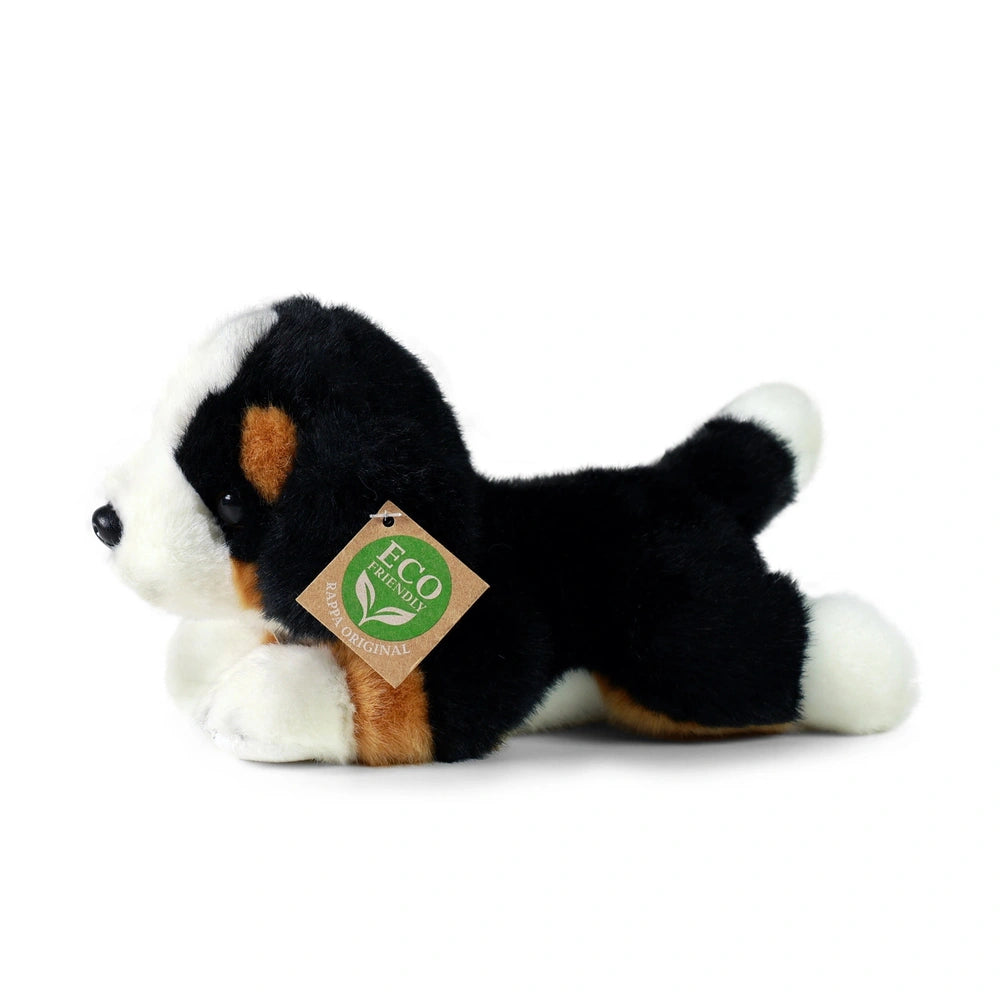 Plush Bernese mountain dog stuffed animal with black and white fur, orange accents, and an eco-friendly tag, lying on its sid