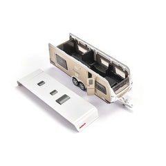 Toy camper van with a glossy white finish and black accents, positioned next to a matte white power strip on a white backgrou