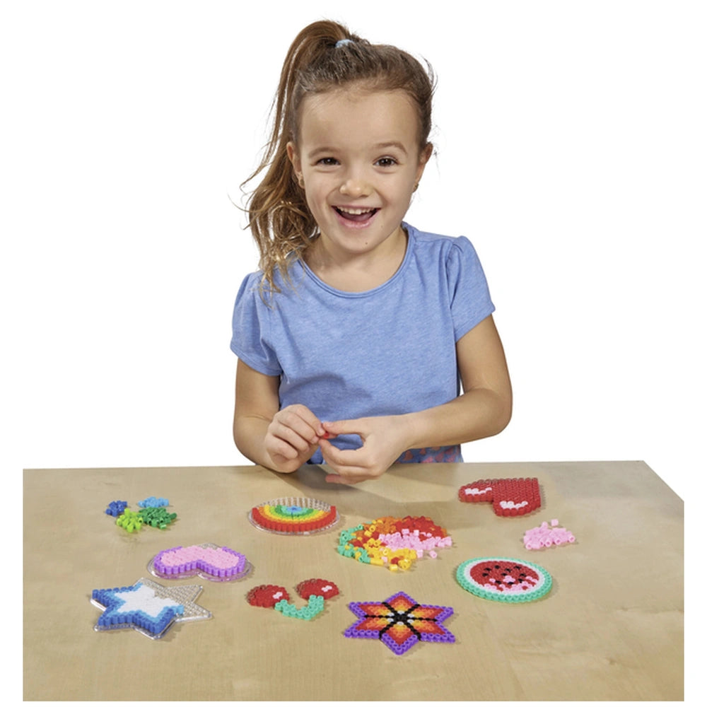 Simba Art & Fun iron-on bead embroidery set with a young girl crafting colorful beads at a bright wooden table.