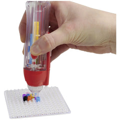 Simba Art & Fun iron-on bead embroidery device dispensing colorful beads on a white grid surface.