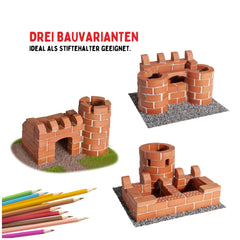 Teifoc castle set features three-dimensional brick structures on a gravel and grass surface, with pencils nearby.