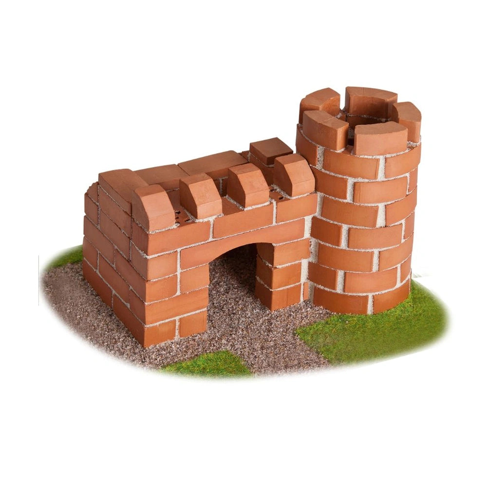 Teifoc castle made of red bricks sits on green grass, featuring a square base, archway, and a small tower.